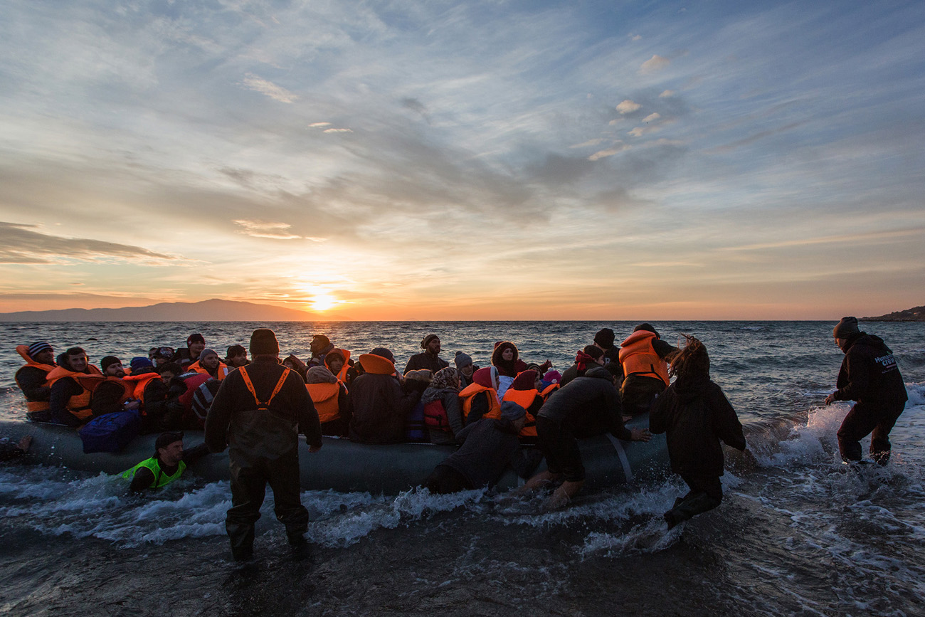 Vapaaehtoisten joukko ottaa venettä vastaan. Matkan viimeiset metrit ovat usein kohtalokkaita kivikkoisesta rannasta johtuen. Kuva: Sami Lensu